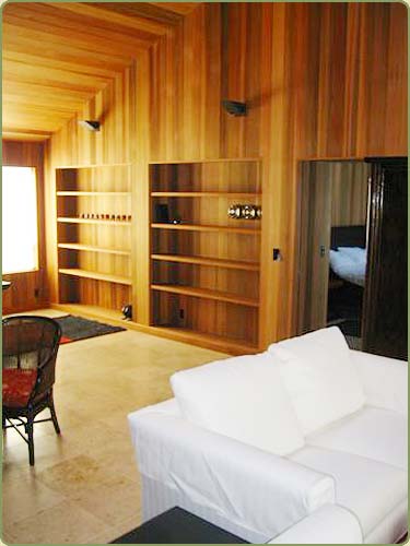picture of a livingroom with wall paneling and shelves built of red cedar tongue and groove
