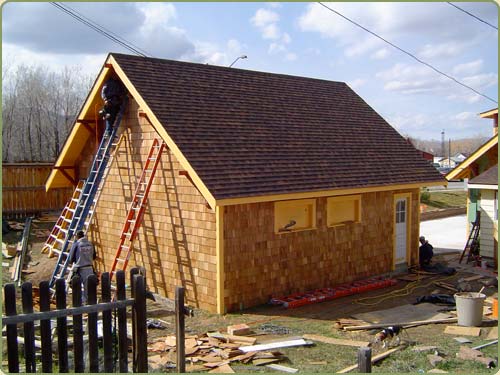 image of a carpenter installing western red cedar shingles as siding for a garage